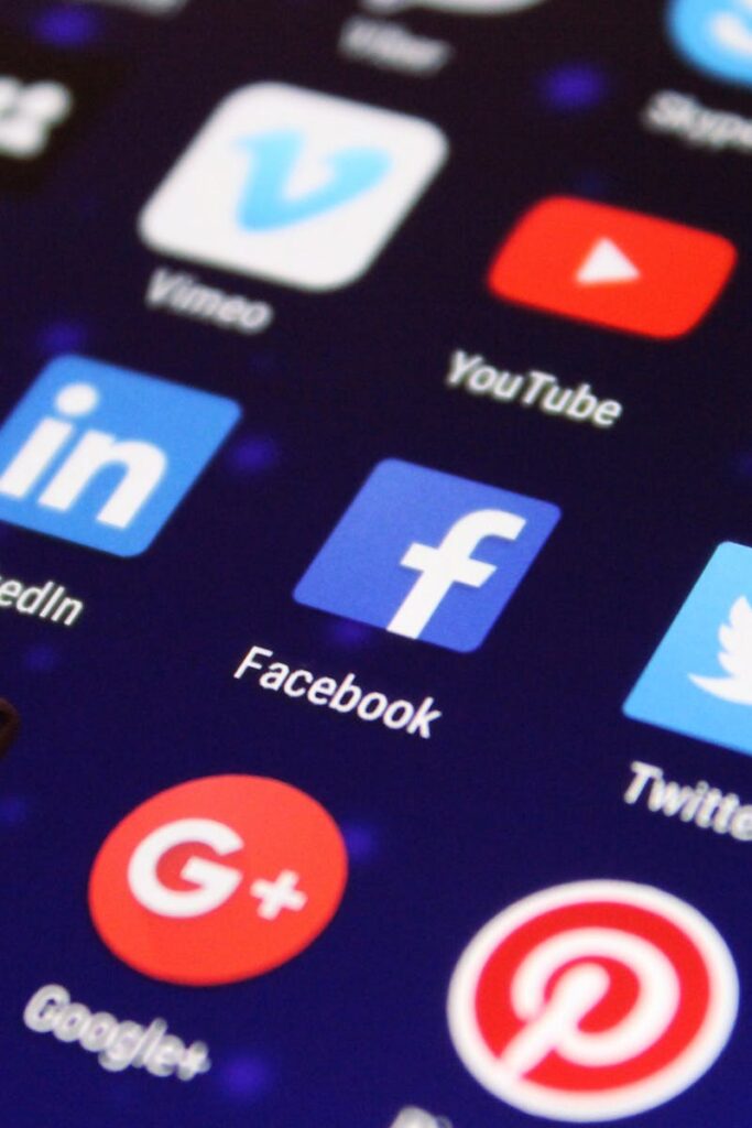 Close-up of a smartphone screen showing various social media app icons such as Facebook and Twitter.